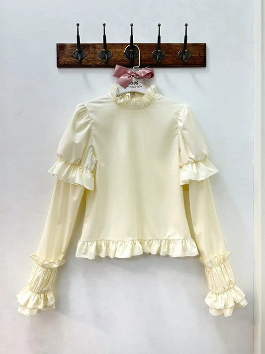 クリーム色のフリルネックラインの長袖ブラウス