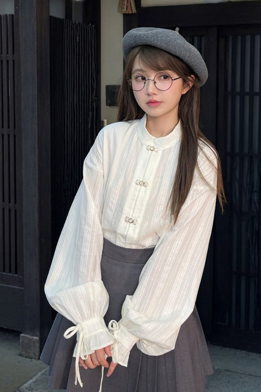 袖口にセルフタイストラップが付いた白いチャイナドレス風シャツ