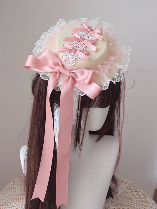 Chapeau plat beige avec détails en dentelle et nœud papillon rose